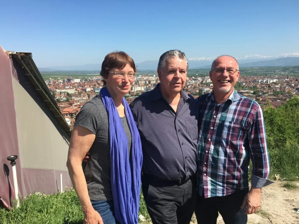 Henk, Anneke en John Arnott in Kosovo met op de achtergrond Gjakove