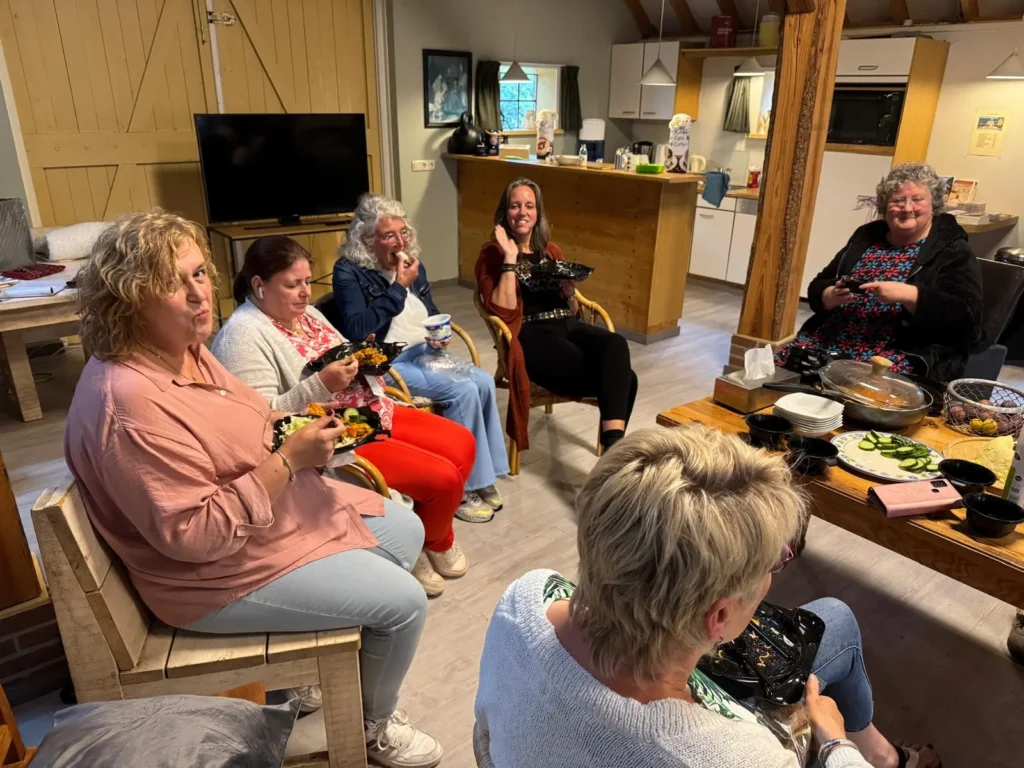 groep mensen die in gezellige ruimte bij elkaar zitten.