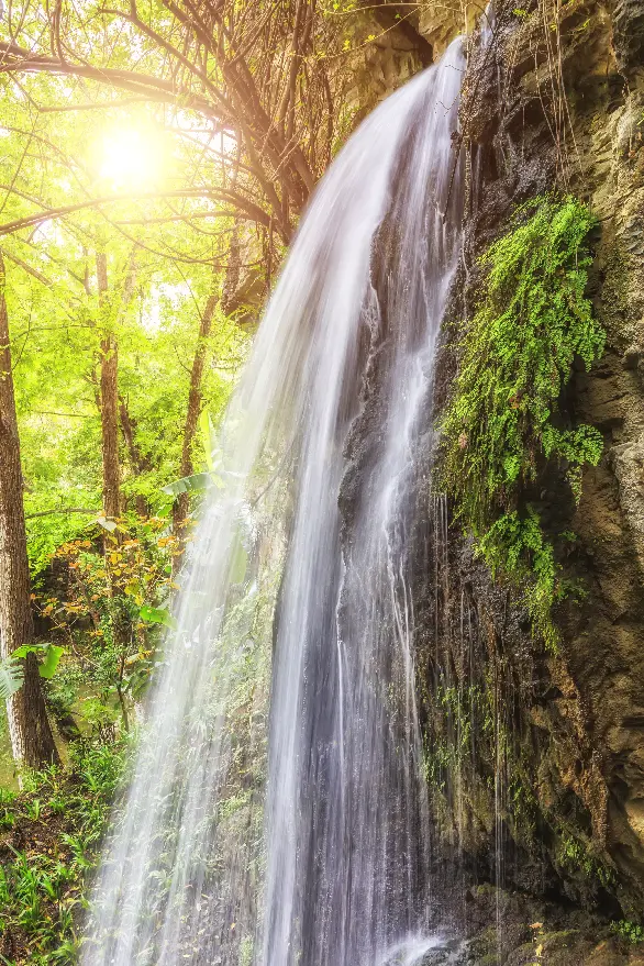 waterval in het bos met zon die schijnt door de bomen