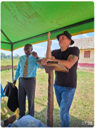 Klaas de Weerd  met hoed op, spreekt in een tent. 