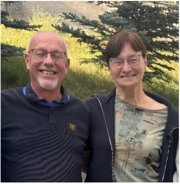 Henk en Anneke lachend op foto met boom en heuvel op achtergrond