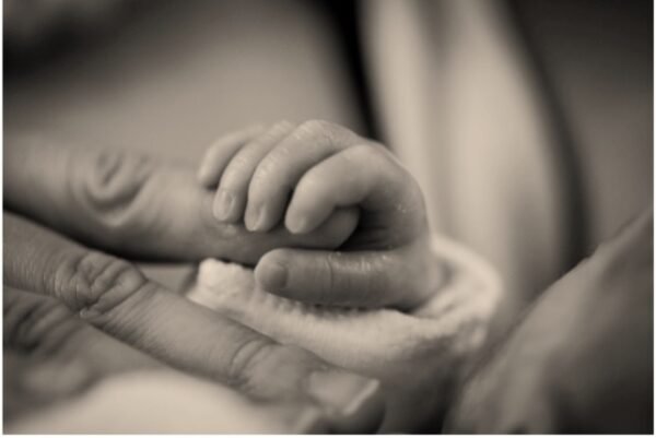 Babyhandje pakt vinger van vader vast